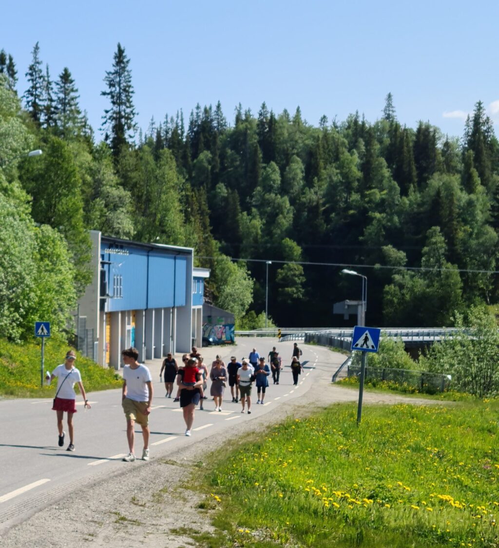 Tjue personer som vandrer langs en vei i Røyrvik