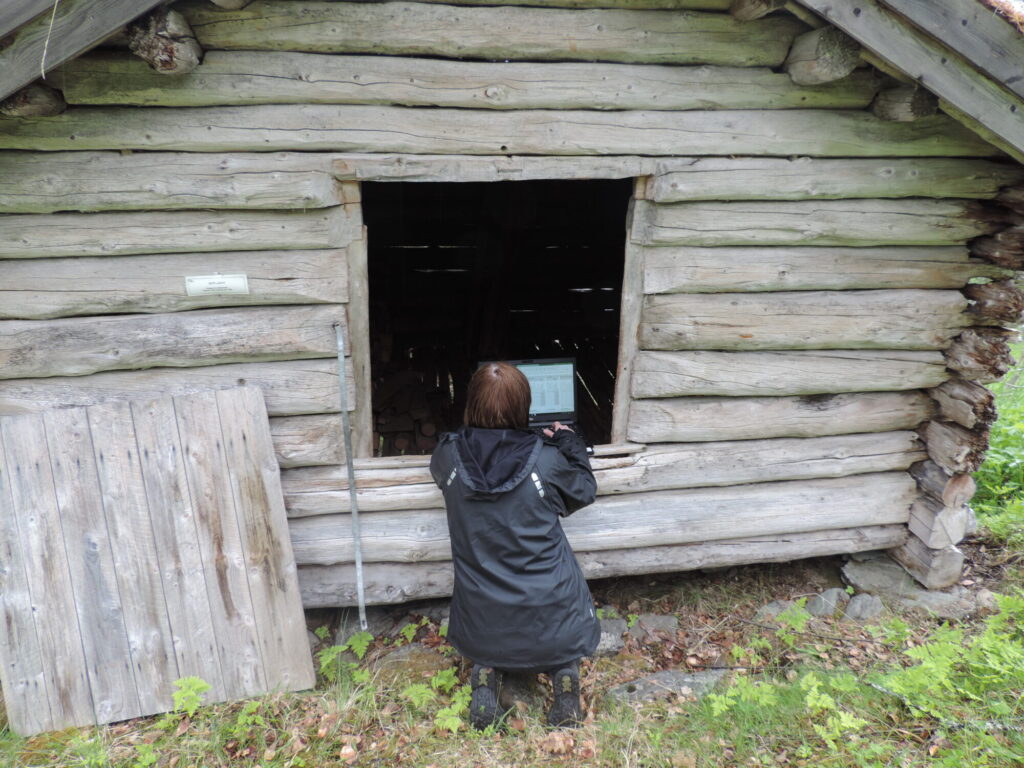 Peron sitter på kne i døråpningen på et gammelt kvernhus